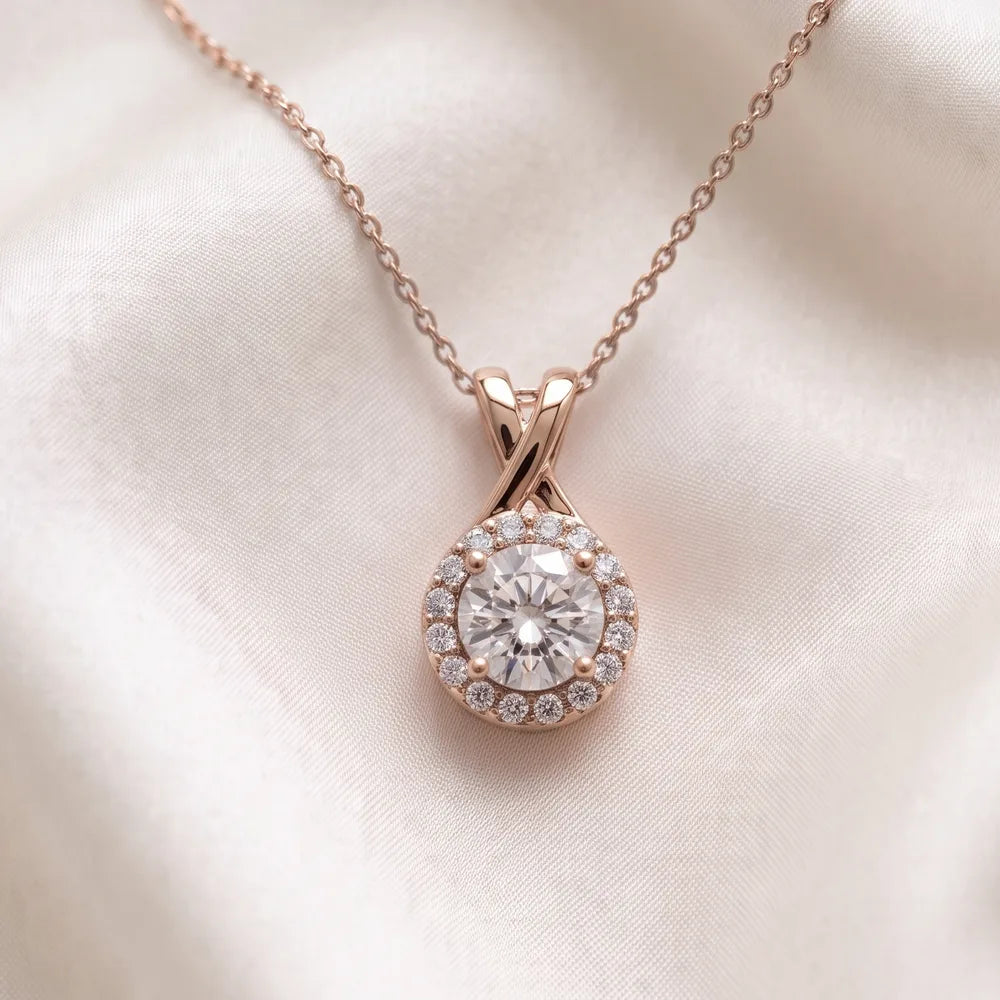 Rose gold halo pendant with a round diamond, resting on ivory silk