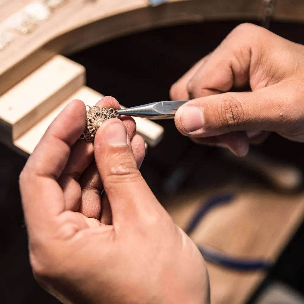 Stone setter at the workbench holding a ring and setting tool